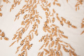 A hand-beaded embroidery fabric, with a pattern of fern-like leaves in a warm, copper-gold color palette.