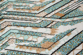 An Art Deco style geometric beaded fabric, with a mosaic or shattered pattern in gold, aqua, and black.