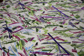 An abstract embroidery fabric on black tulle, with a graffiti-like pattern of lines made from neon green, pink, and purple sequins and thread.