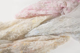 A fabric with 3D textured flowers and sequin embroidery, shown in various pastel color options.