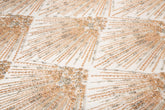 An Art Deco style beaded fabric, with a radiating palm leaf or sunburst pattern in a rose gold and silver palette.