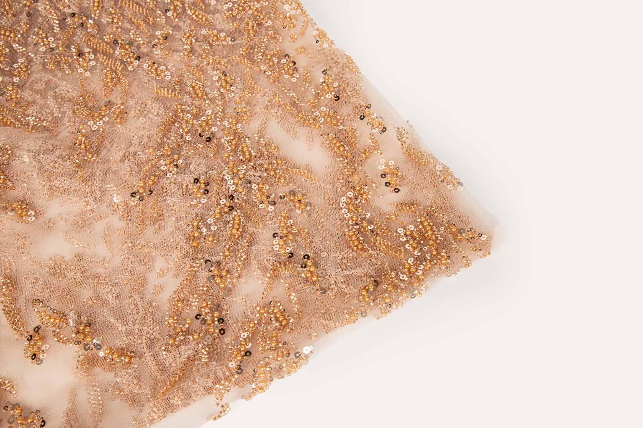 A hand-beaded embroidery fabric, with a pattern of fern-like leaves in a warm, copper-gold color palette.
