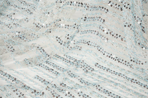 A fine beaded embroidery fabric, with a vertical dashed-line pattern resembling rain, in shades of ice blue and silver.