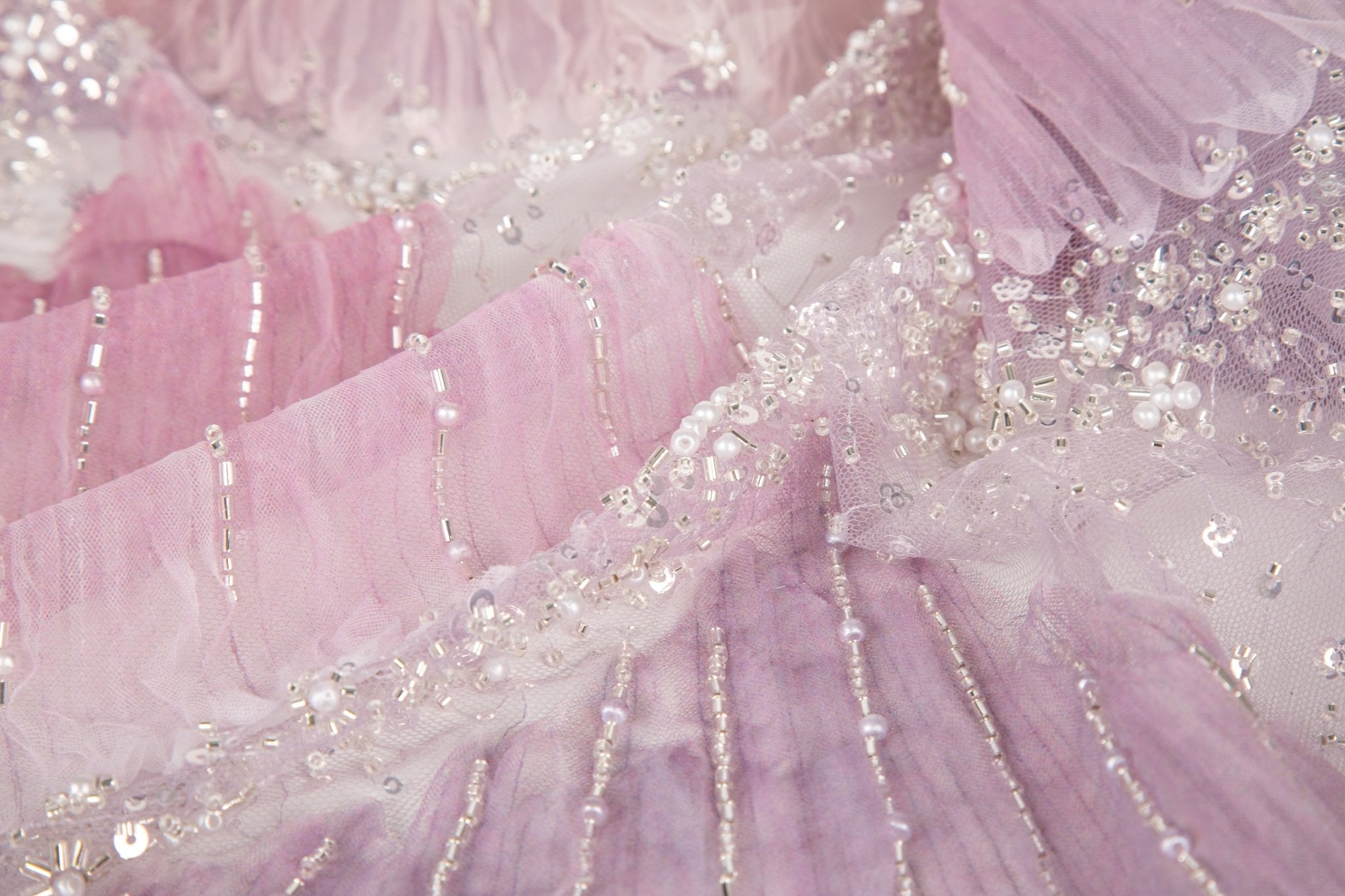A 3D embroidery fabric with ribbon scallop motifs in a pink and lilac gradient.