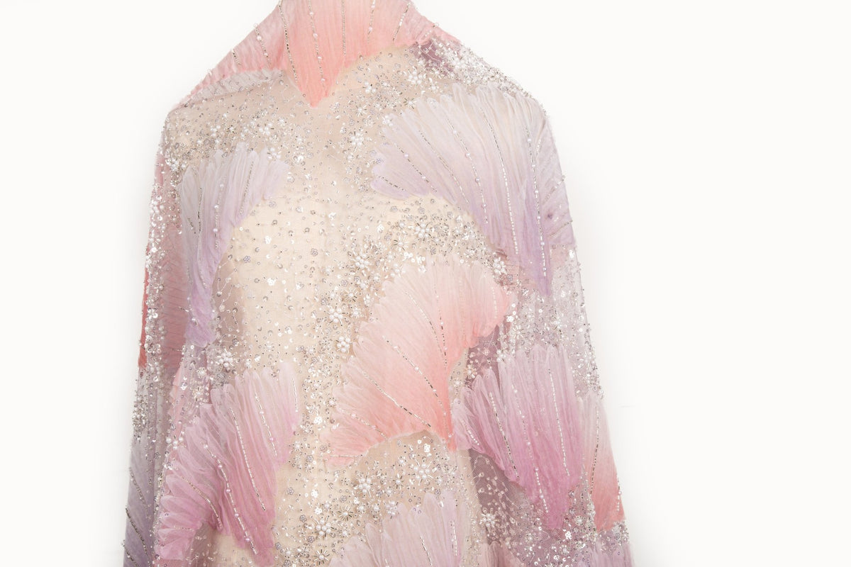 A 3D embroidery fabric with ribbon scallop motifs in a pink and lilac gradient.