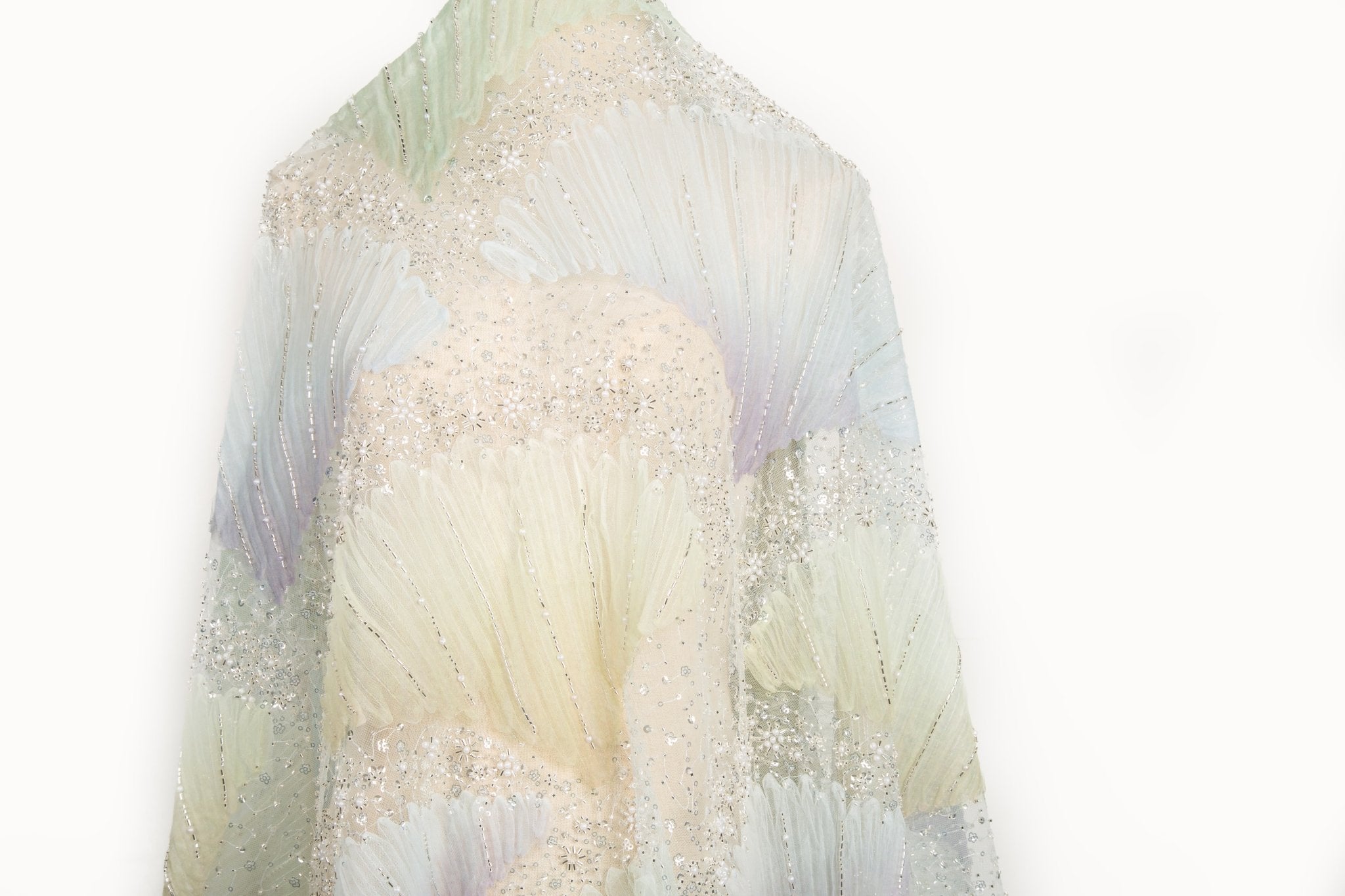 A 3D embroidery fabric with ribbon scallop motifs in a yellow, green, blue, and lilac gradient.
