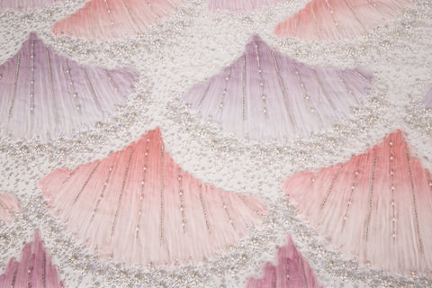 A 3D embroidery fabric with ribbon scallop motifs in a pink and lilac gradient.