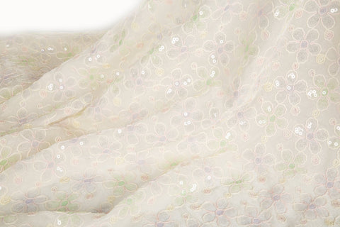 White mesh fabric with small floral embroidery in lavender and light green threads, accented with iridescent sequins, draped softly.