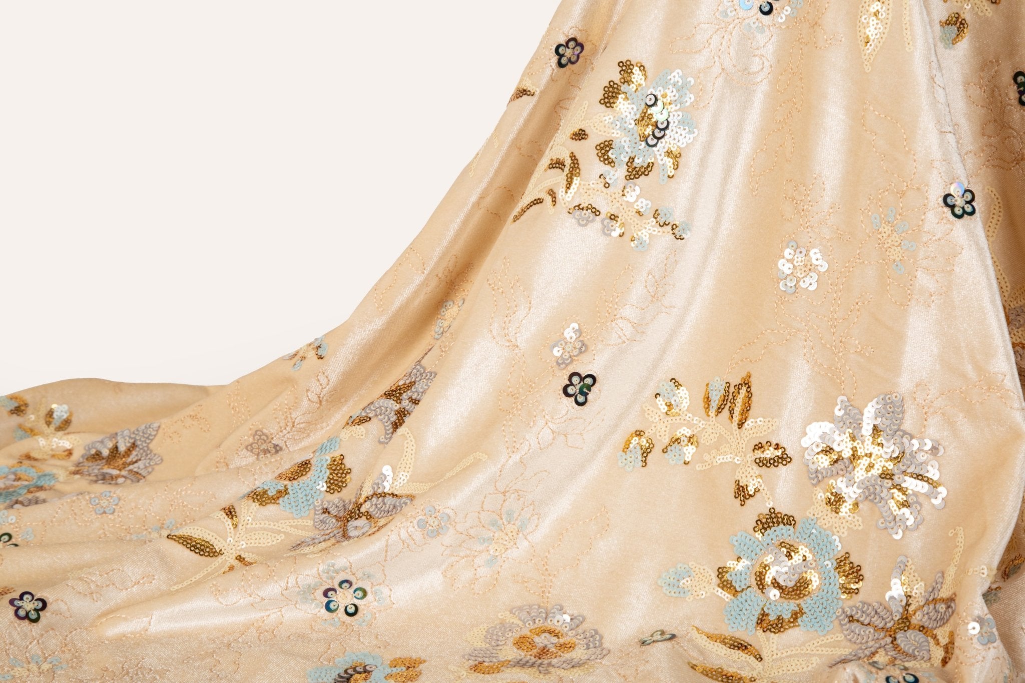 A sequin floral embroidery fabric on a cream velvet base, with blue and gold motifs.

