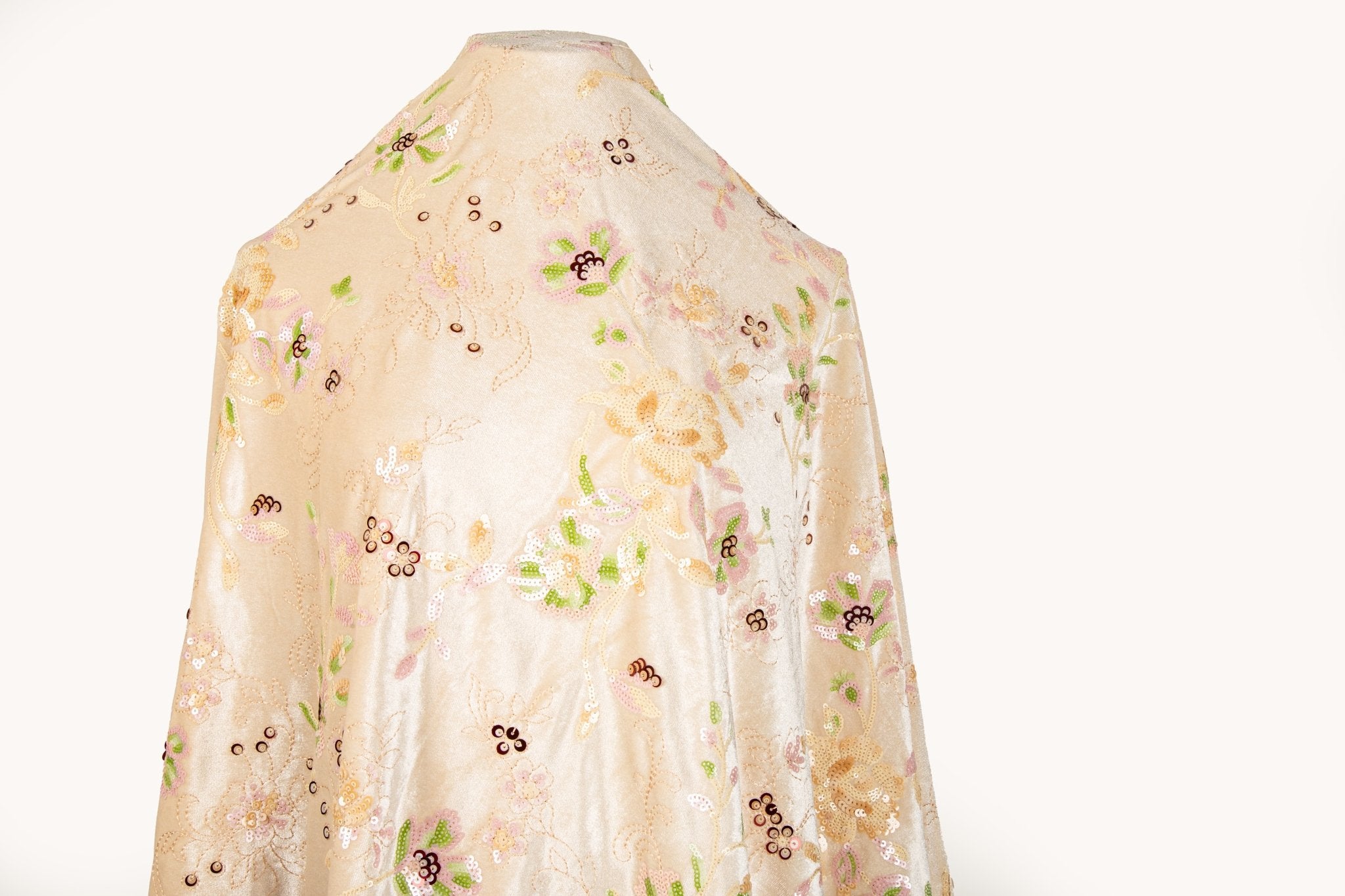 A sequin floral embroidery fabric on a cream velvet base, with pink and green motifs.
