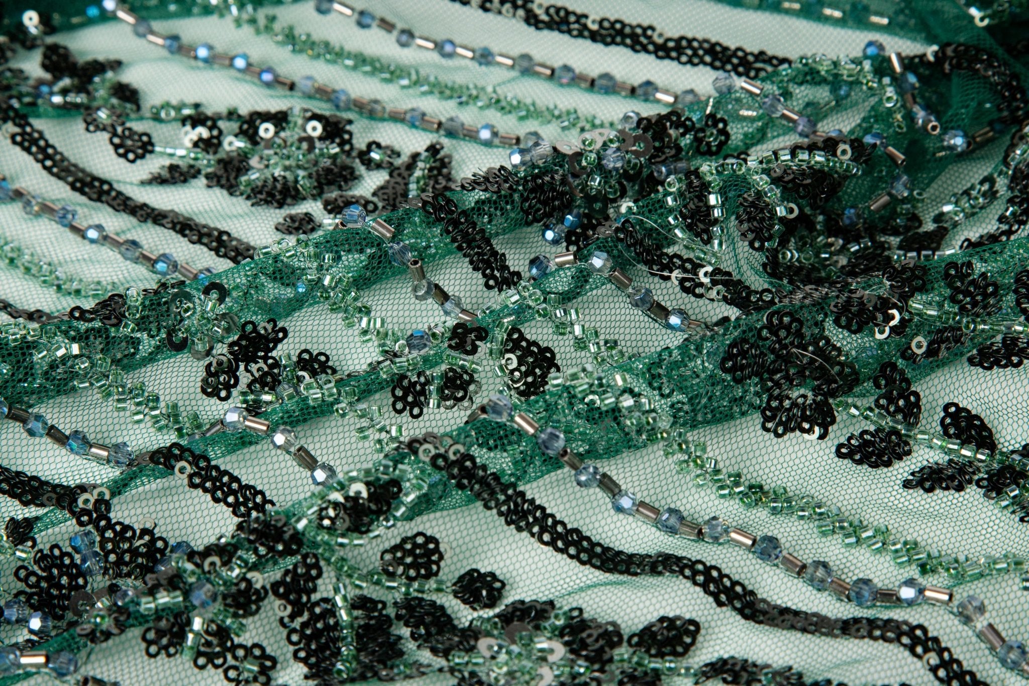 An emerald green Art Deco beaded fabric, with concentric, eye-shaped patterns in black sequins and beads.
