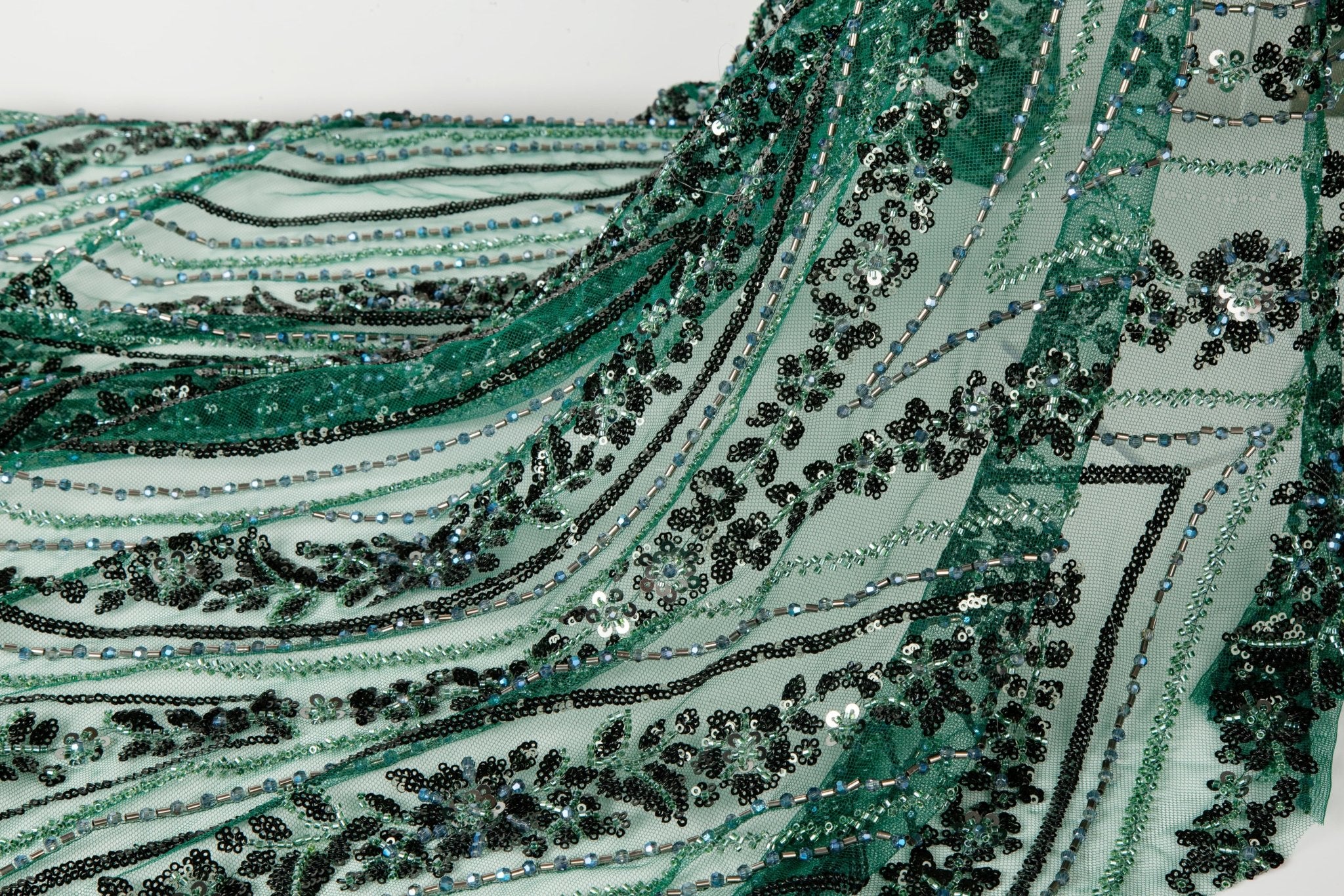 An emerald green Art Deco beaded fabric, with concentric, eye-shaped patterns in black sequins and beads.
