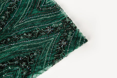 An emerald green Art Deco beaded fabric, with concentric, eye-shaped patterns in black sequins and beads.
