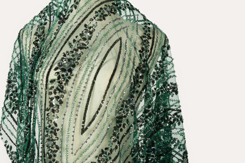 An emerald green Art Deco beaded fabric, with concentric, eye-shaped patterns in black sequins and beads.
