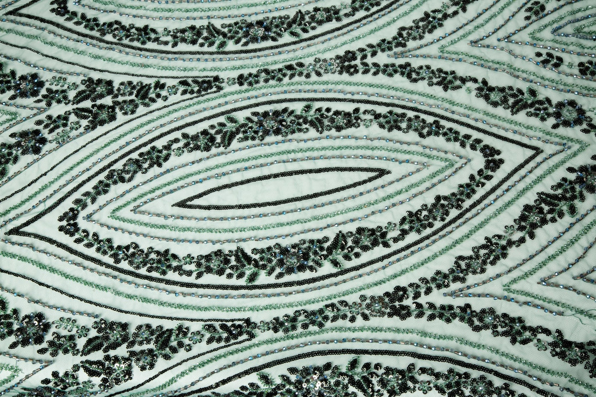An emerald green Art Deco beaded fabric, with concentric, eye-shaped patterns in black sequins and beads.
