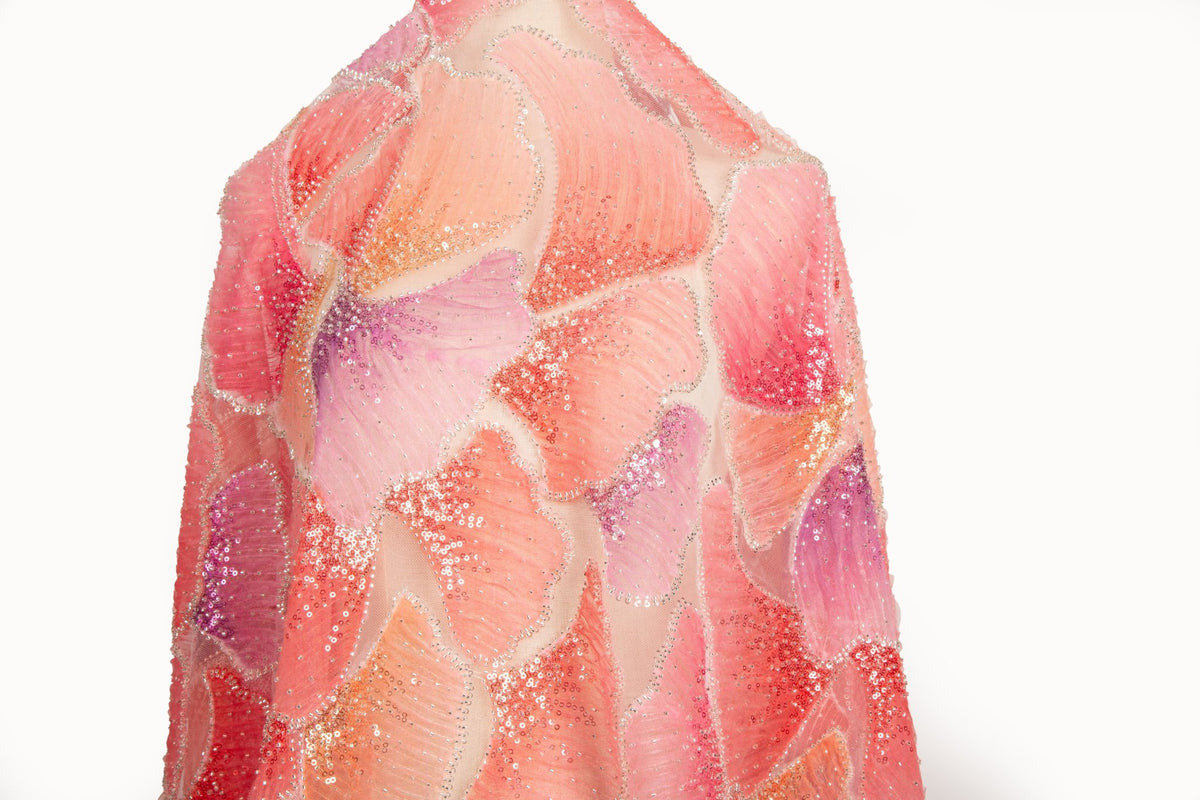 A 3D ribbon and bead embroidery fabric, with feathered petal motifs in a coral and purple gradient.
