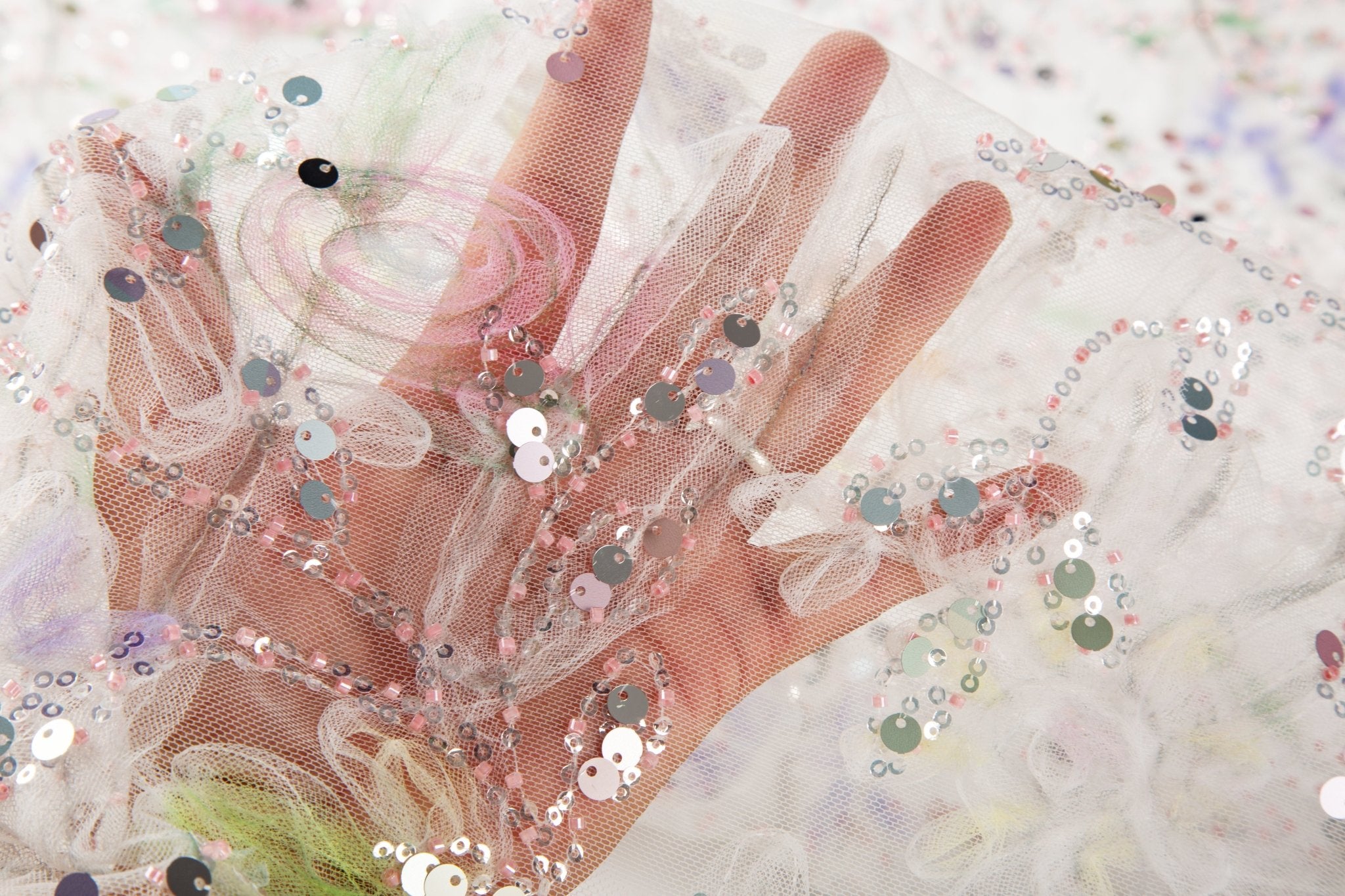 A 3D ruched embroidery fabric with a soft texture, in a palette of mint green, lilac, and pink.
