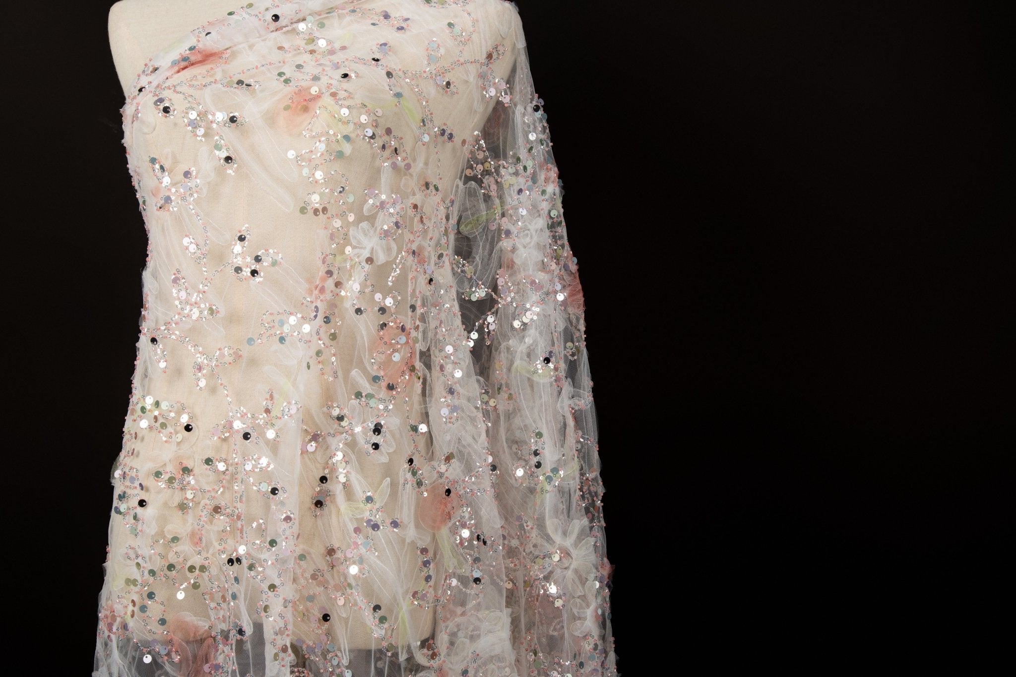 A 3D ruched embroidery fabric with a soft texture, in a palette of peach-pink and cream.
