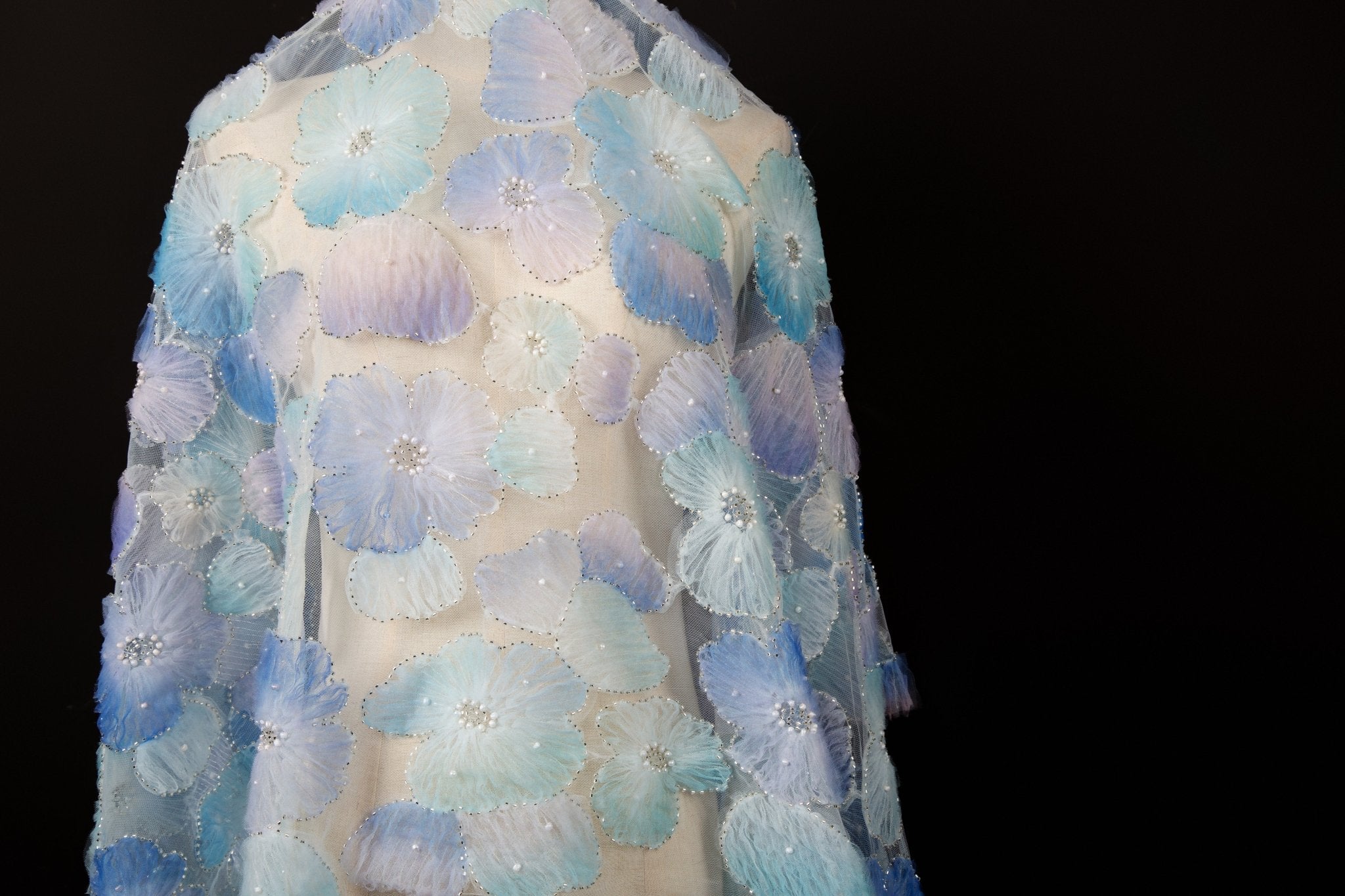 Ice blue, lavender, and white crinkle ribbon embroidered floral fabric.