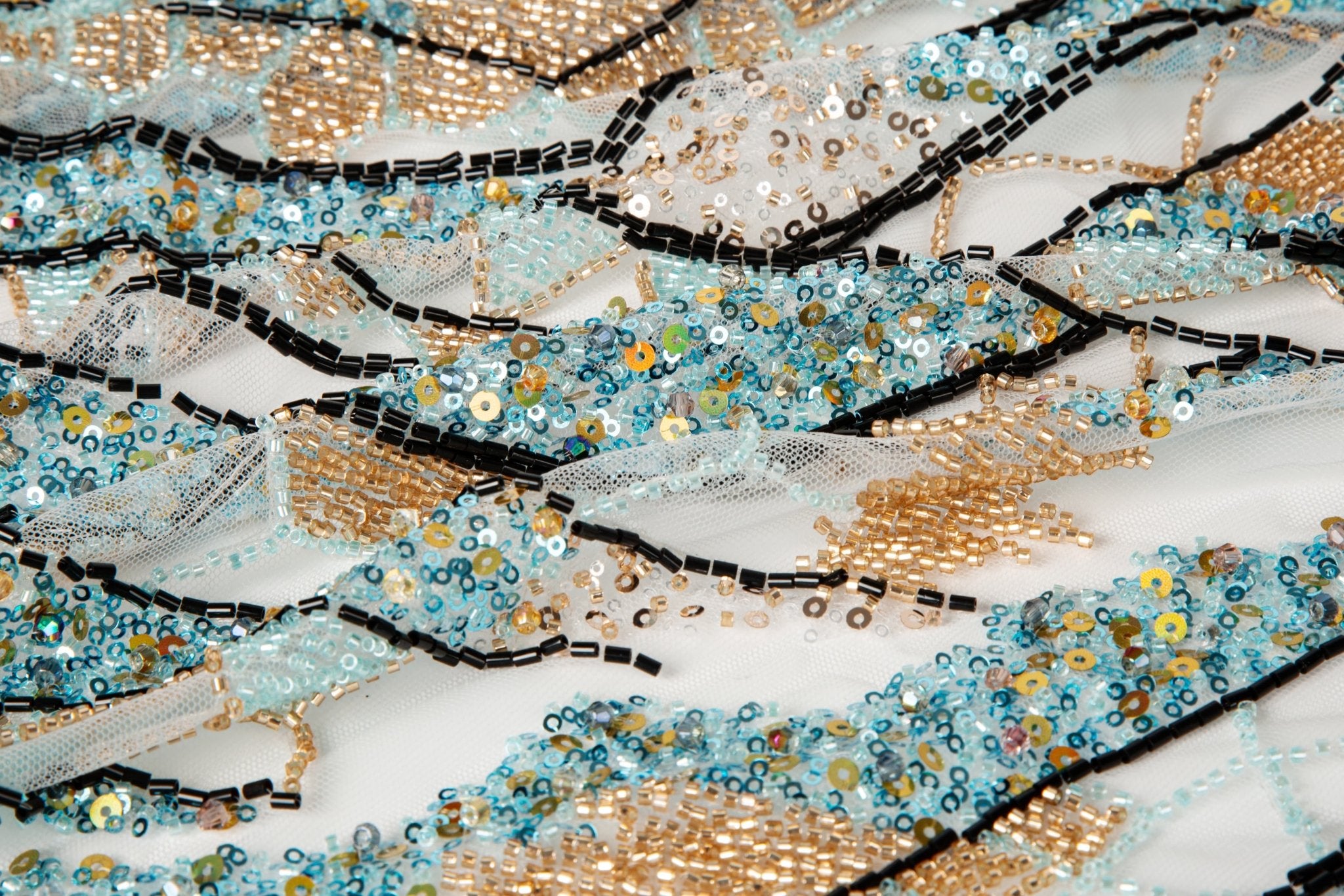 An Art Deco style geometric beaded fabric, with a mosaic or shattered pattern in gold, aqua, and black.
