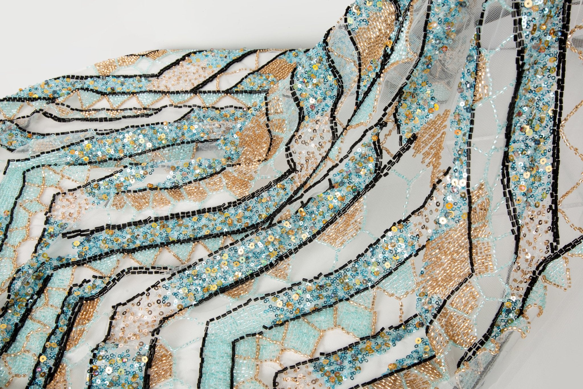 An Art Deco style geometric beaded fabric, with a mosaic or shattered pattern in gold, aqua, and black.
