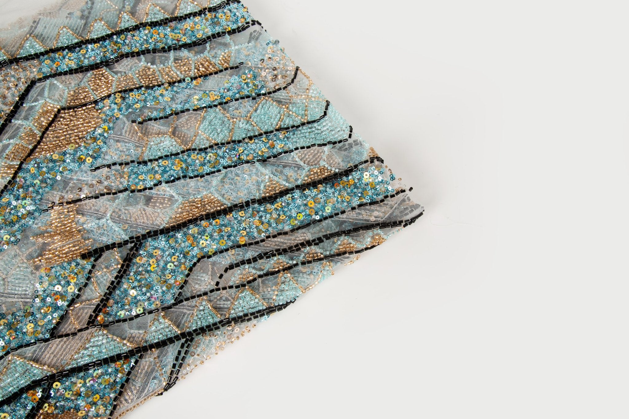 An Art Deco style geometric beaded fabric, with a mosaic or shattered pattern in gold, aqua, and black.
