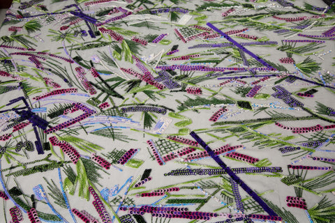 An abstract embroidery fabric on black tulle, with a graffiti-like pattern of lines made from neon green, pink, and purple sequins and thread.

