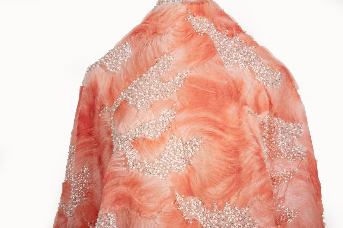 A 3D ribbon and beaded embroidery fabric in coral pink.