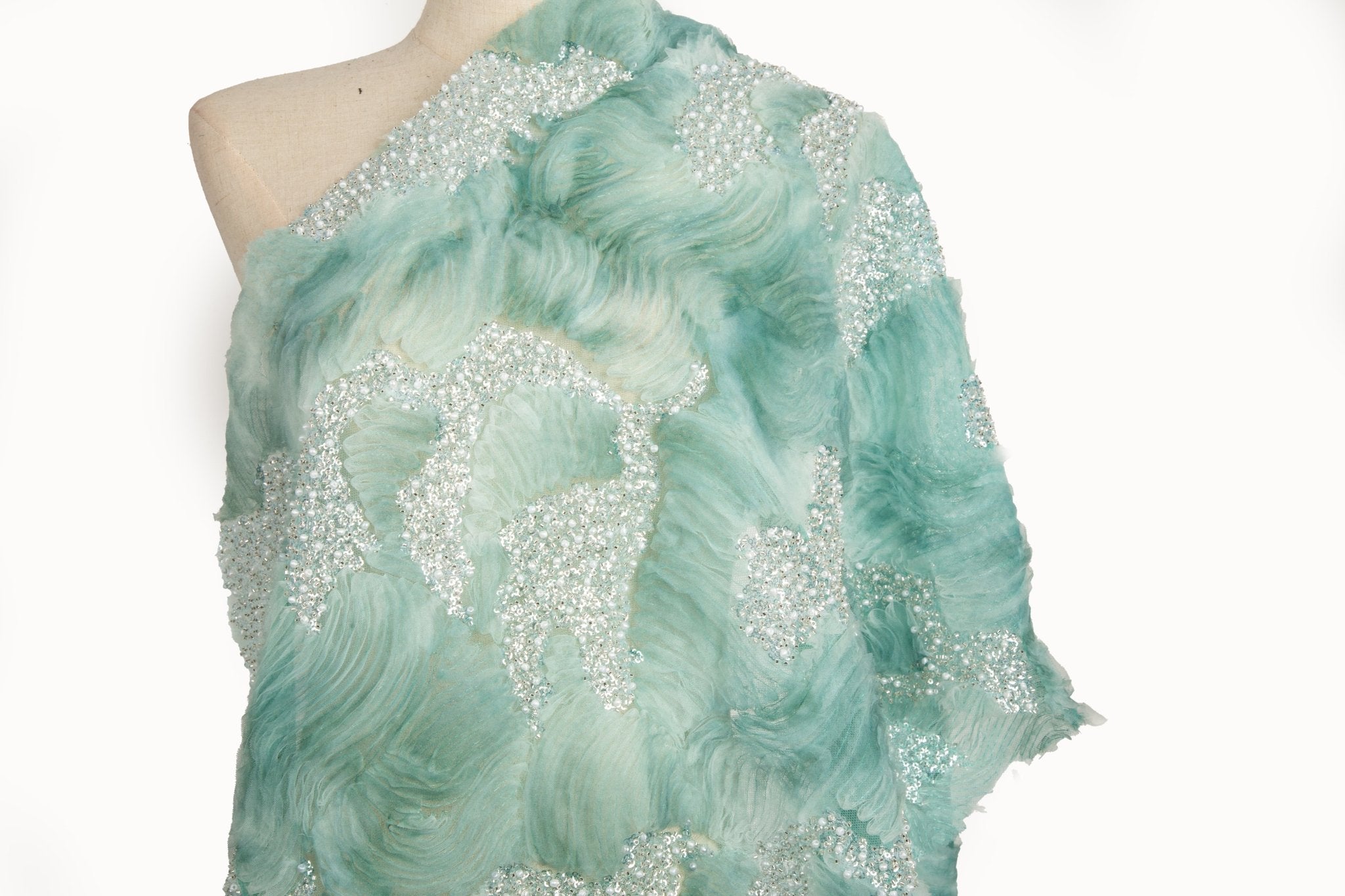 A 3D ribbon and beaded embroidery fabric in mint green.