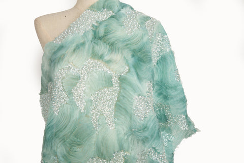 A 3D ribbon and beaded embroidery fabric in mint green.