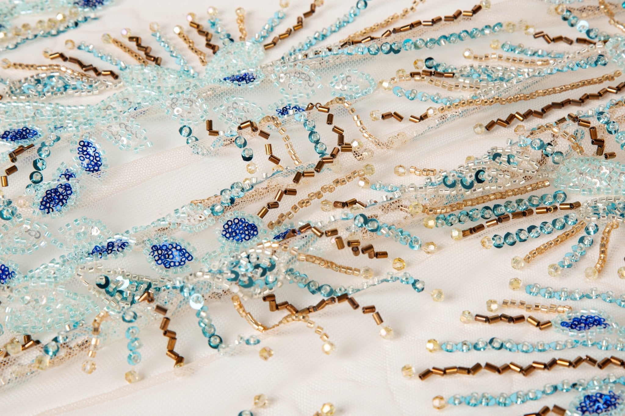 An Art Deco style beaded fabric, with a radiating fireworks or sunburst pattern in aqua, royal blue, and bronze.
