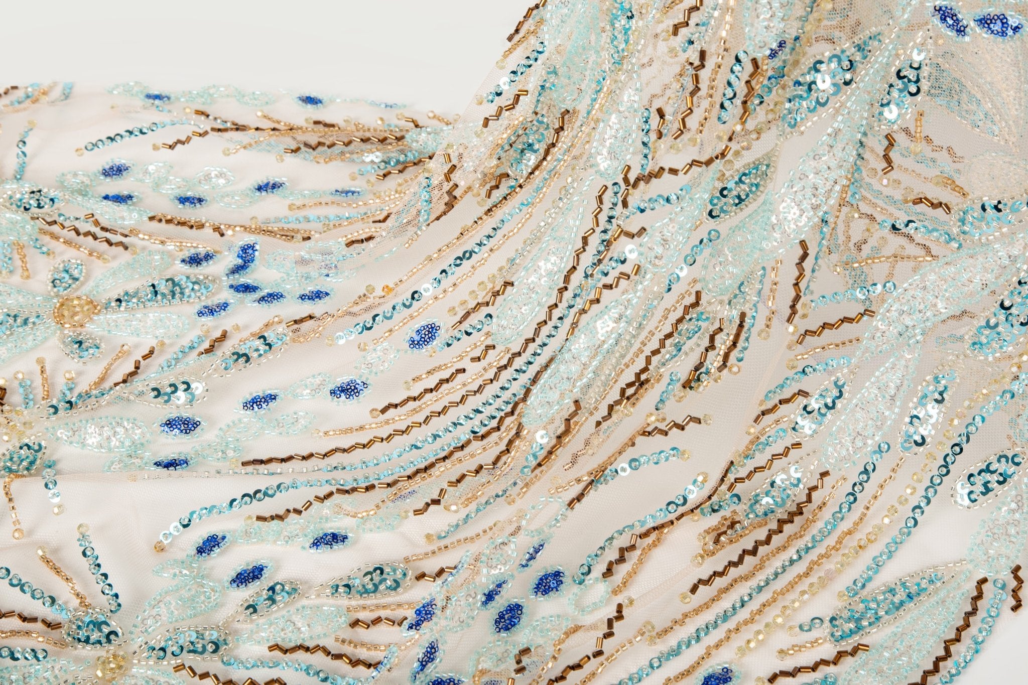 An Art Deco style beaded fabric, with a radiating fireworks or sunburst pattern in aqua, royal blue, and bronze.
