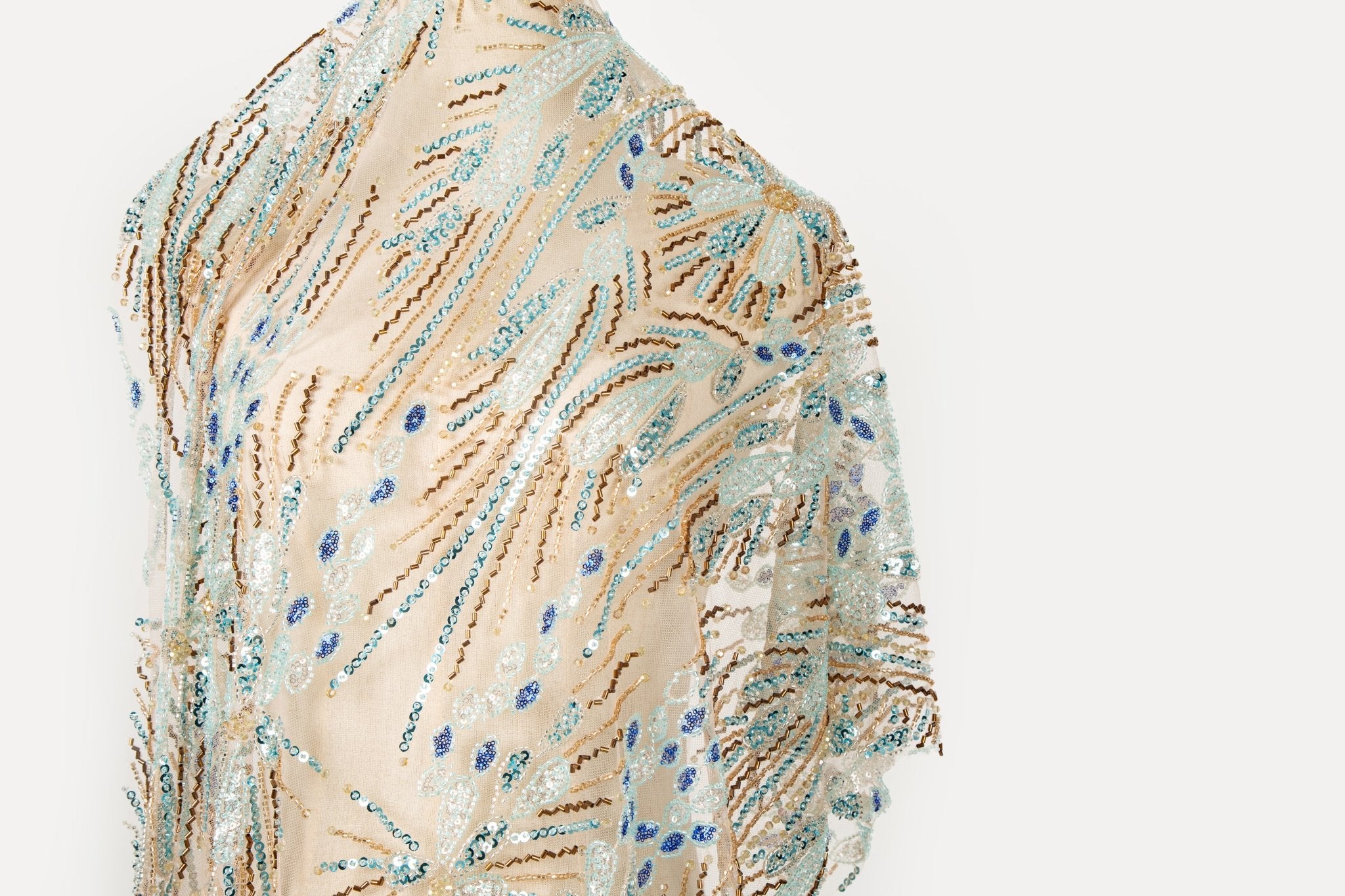 An Art Deco style beaded fabric, with a radiating fireworks or sunburst pattern in aqua, royal blue, and bronze.
