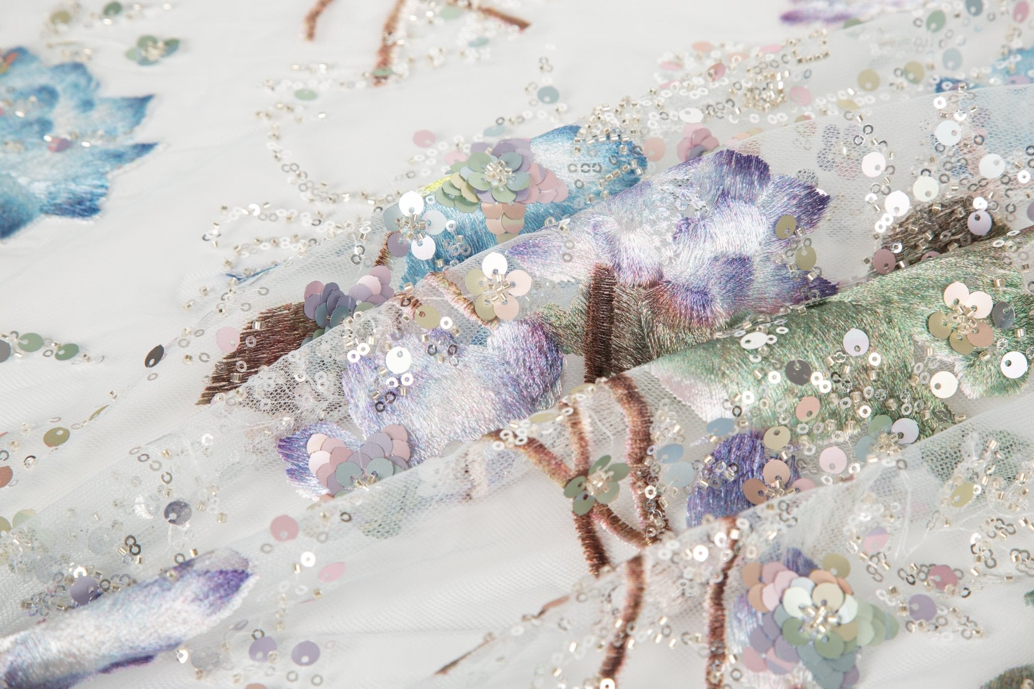 An embroidery fabric on ivory mesh, with a painterly pattern of water lilies in a blue and purple palette.
