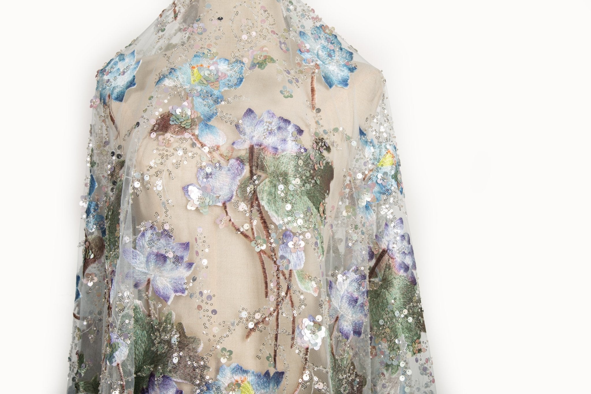 An embroidery fabric on ivory mesh, with a painterly pattern of water lilies in a blue and purple palette.
