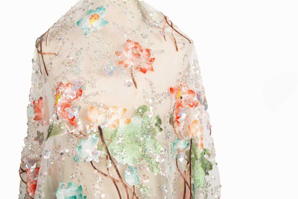 An embroidery fabric on ivory mesh, with a painterly pattern of water lilies in a blue and purple palette.
