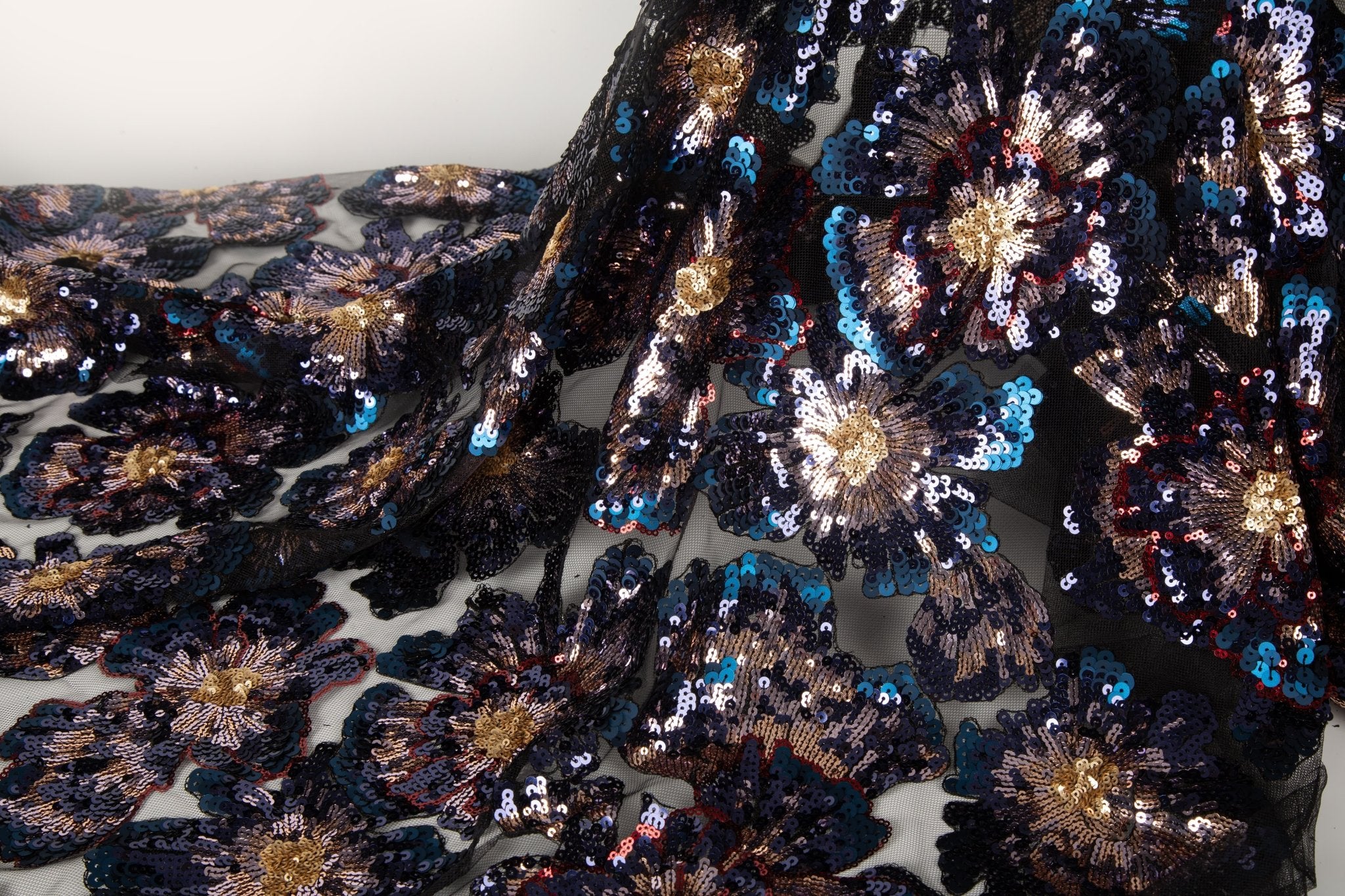 A large floral sequin embroidery fabric on a nude base, with red and pink motifs.
