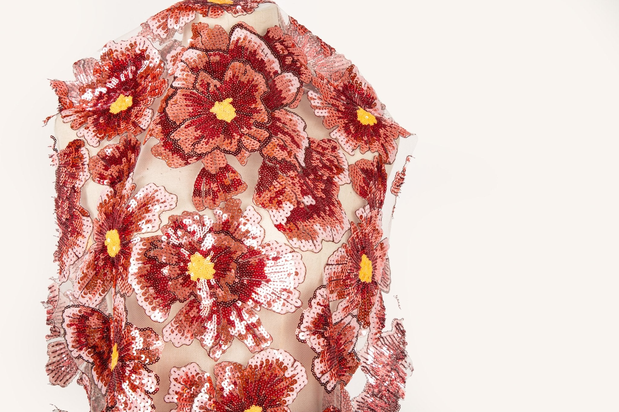 A large floral sequin embroidery fabric on a nude base, with red and pink motifs.
