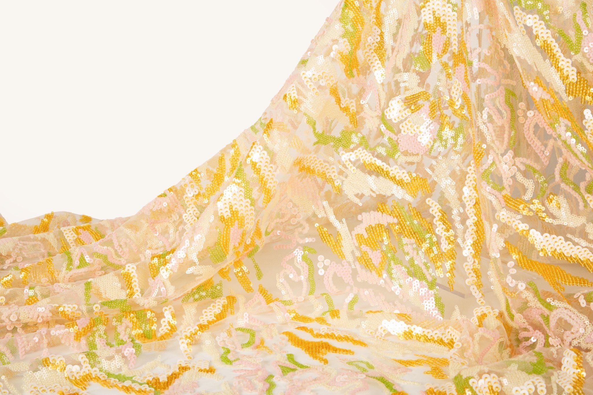 An abstract sequin embroidery fabric with a wavy pattern in yellow, pink, and green.
