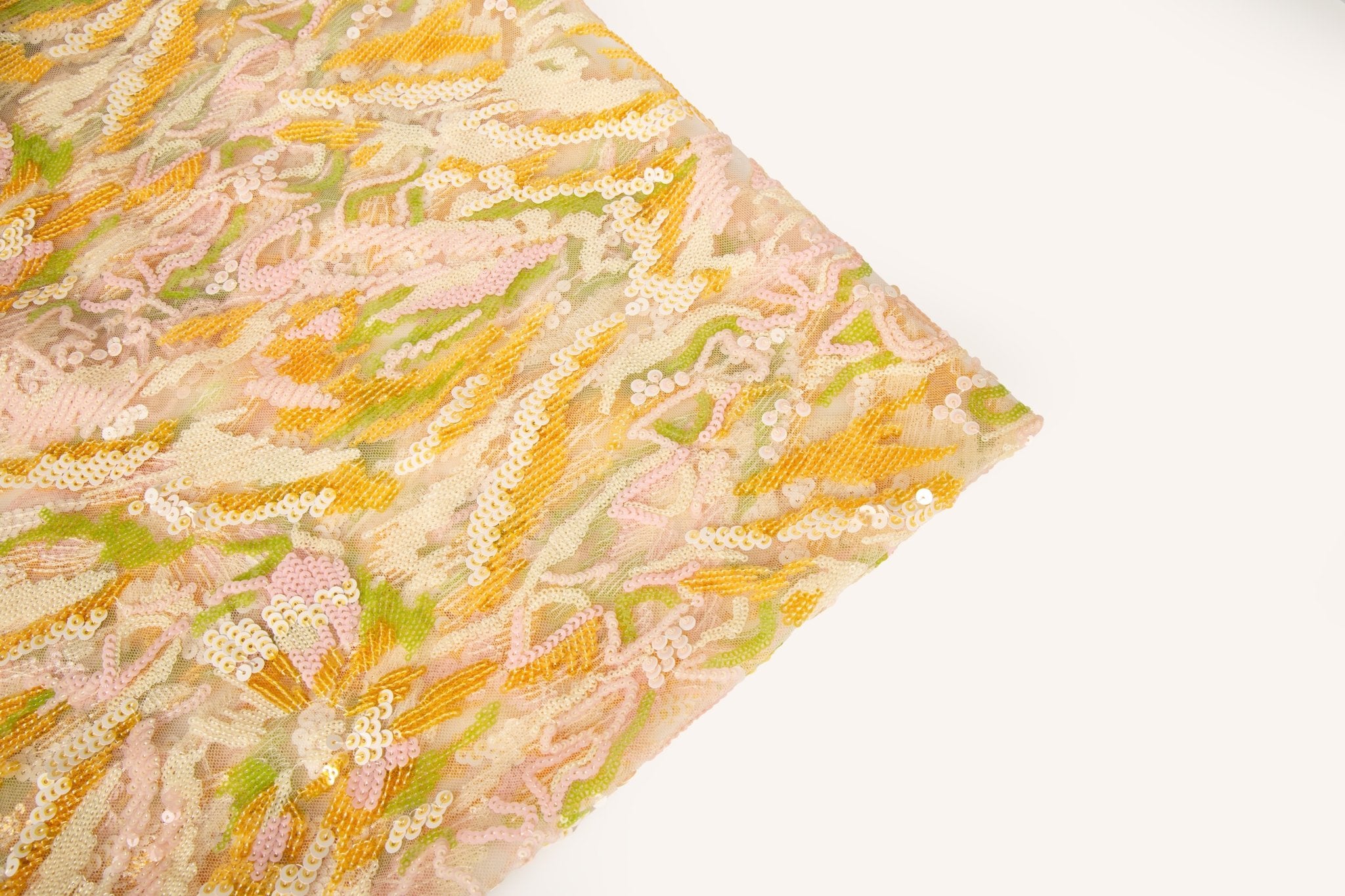 An abstract sequin embroidery fabric with a wavy pattern in yellow, pink, and green.
