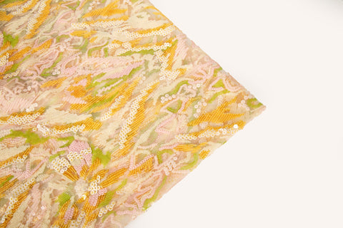 An abstract sequin embroidery fabric with a wavy pattern in yellow, pink, and green.

