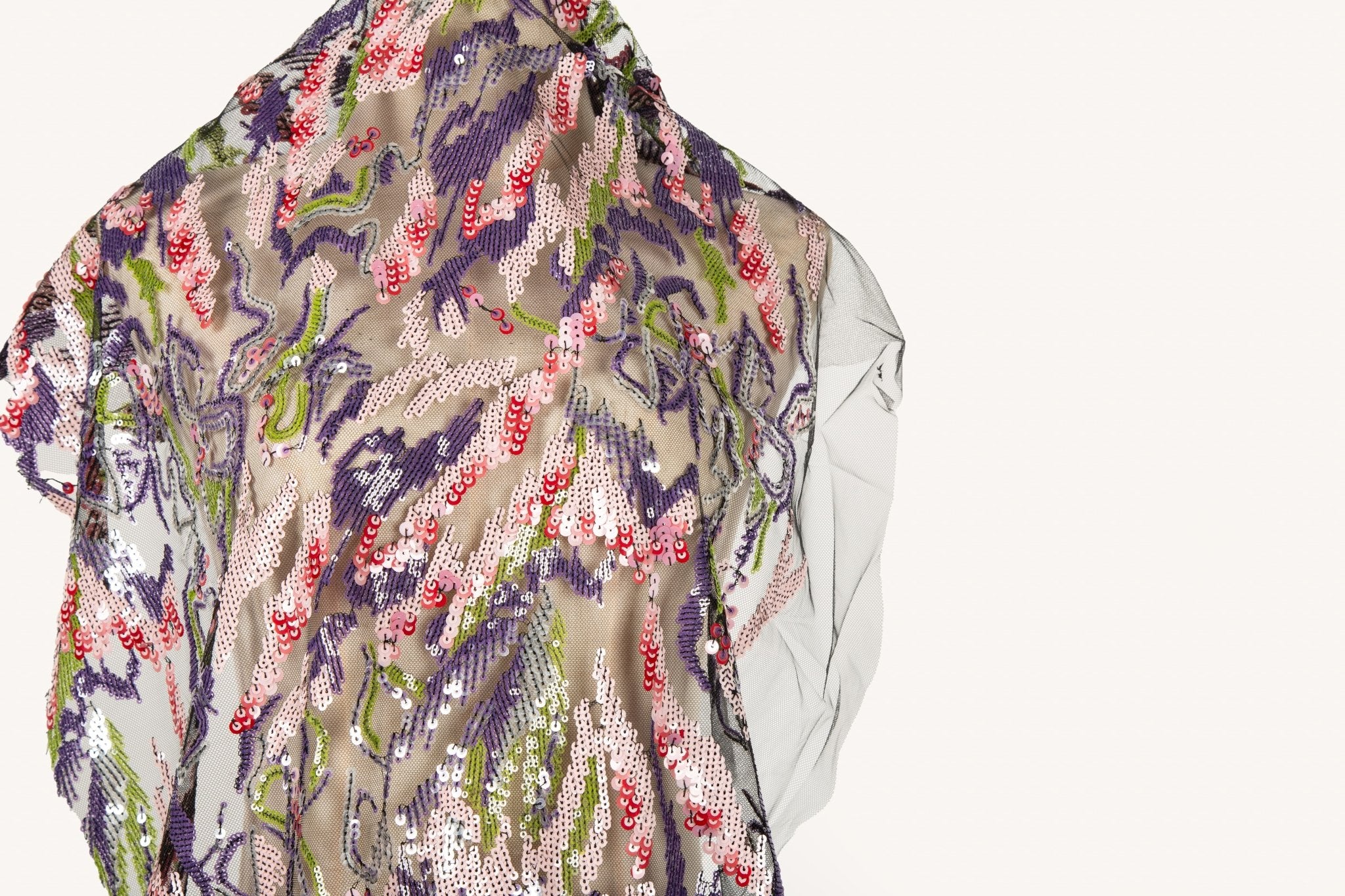 An abstract sequin embroidery fabric on a black base, with a wavy pattern in purple, pink, and green.
