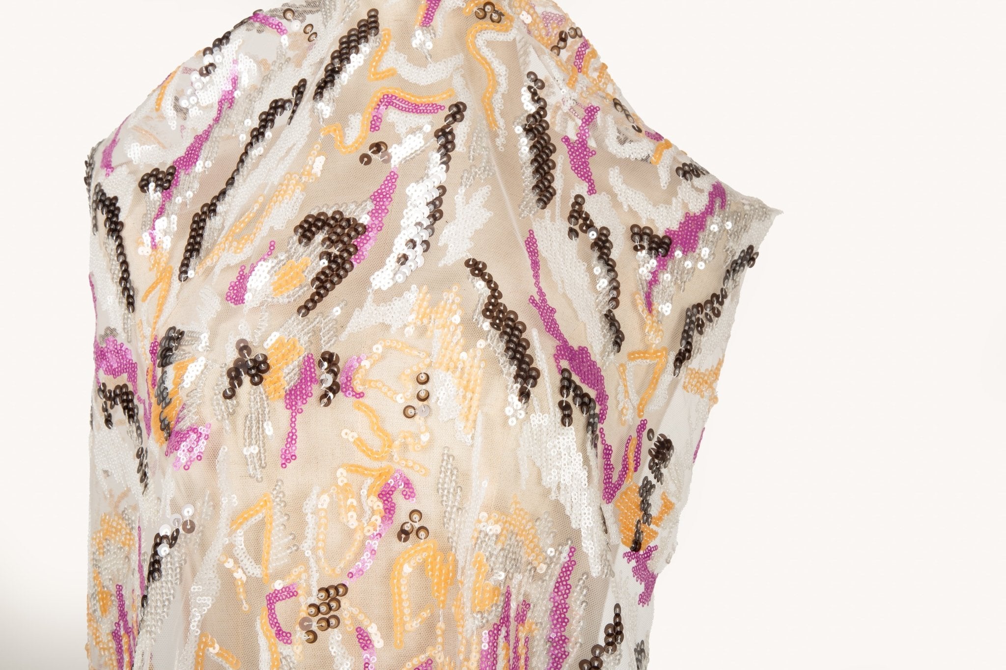 An abstract sequin embroidery fabric with a wavy pattern in fuchsia, yellow, and bronze.
