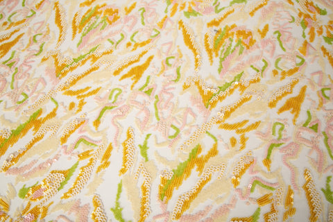  An abstract sequin embroidery fabric with a wavy pattern in yellow, pink, and green.
