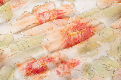 A luxurious floral fabric made with ribbon embroidery, featuring coral-colored flowers and green leaves.
