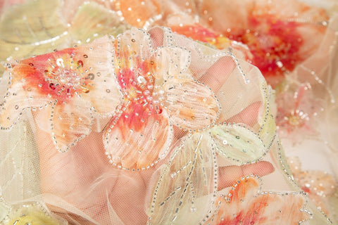A luxurious floral fabric made with ribbon embroidery, featuring coral-colored flowers and green leaves.
