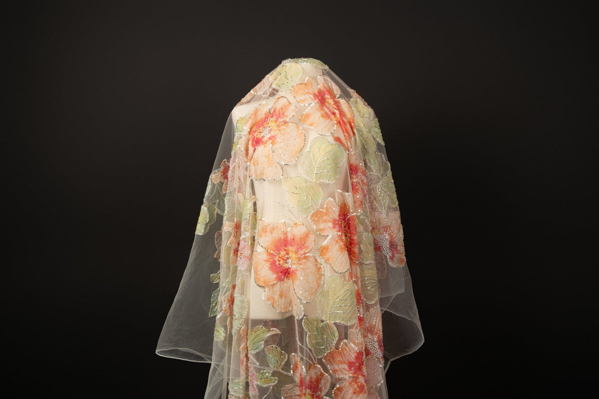 A luxurious floral fabric made with ribbon embroidery, featuring coral-colored flowers and green leaves.
