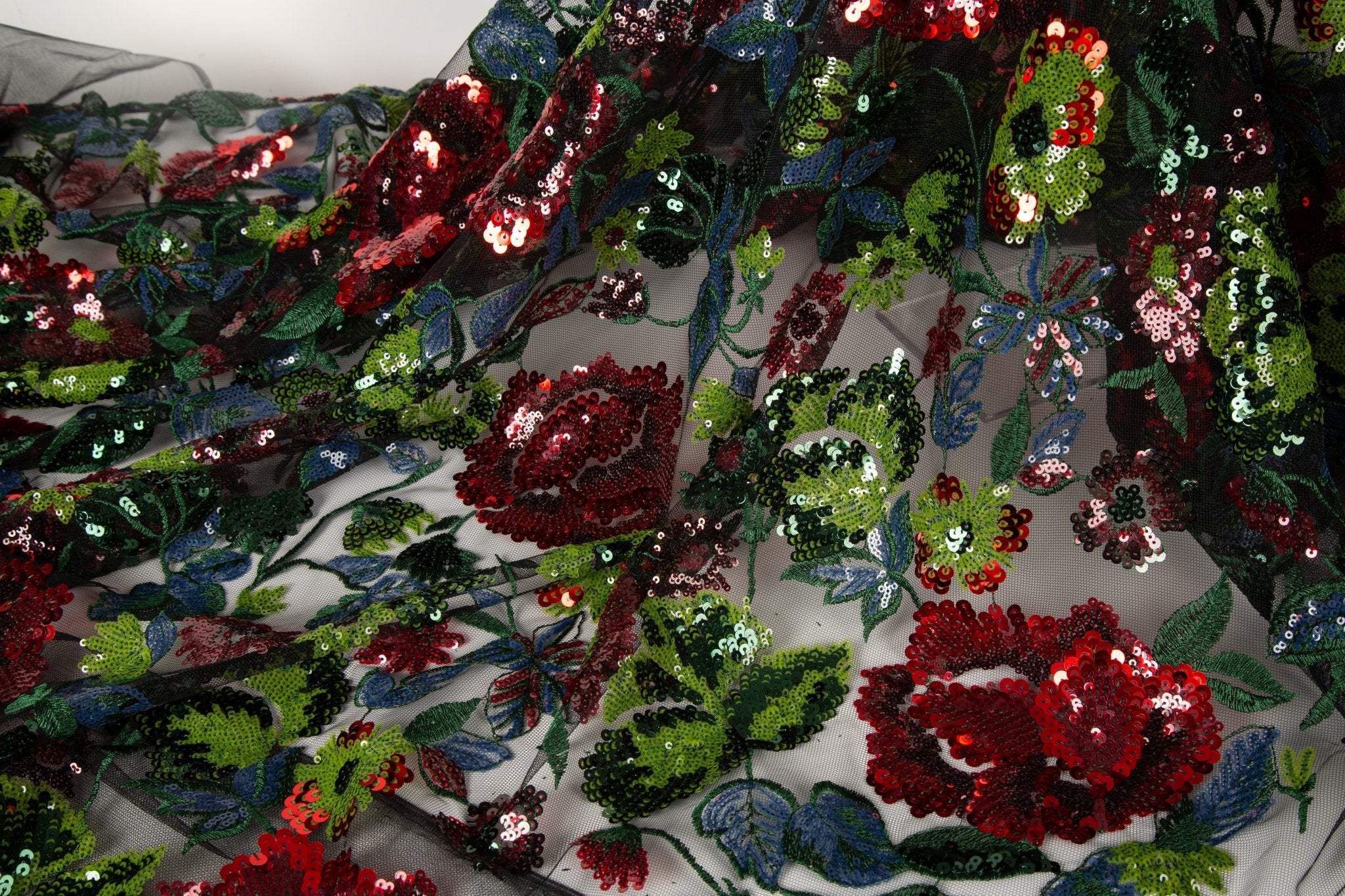 A sequin floral embroidery fabric on a black base, with red and green motifs.