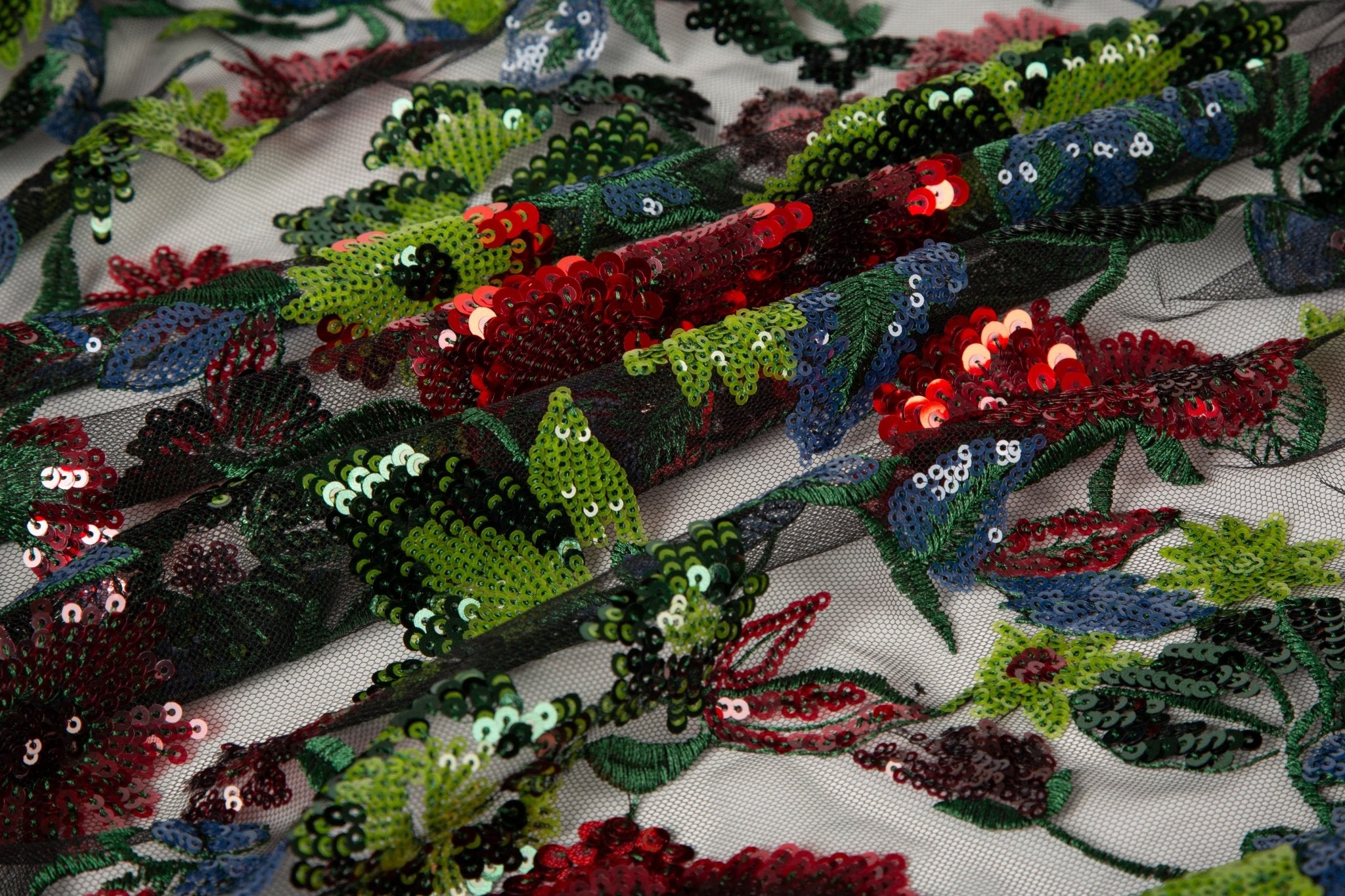 A sequin floral embroidery fabric on a black base, with red and green motifs.