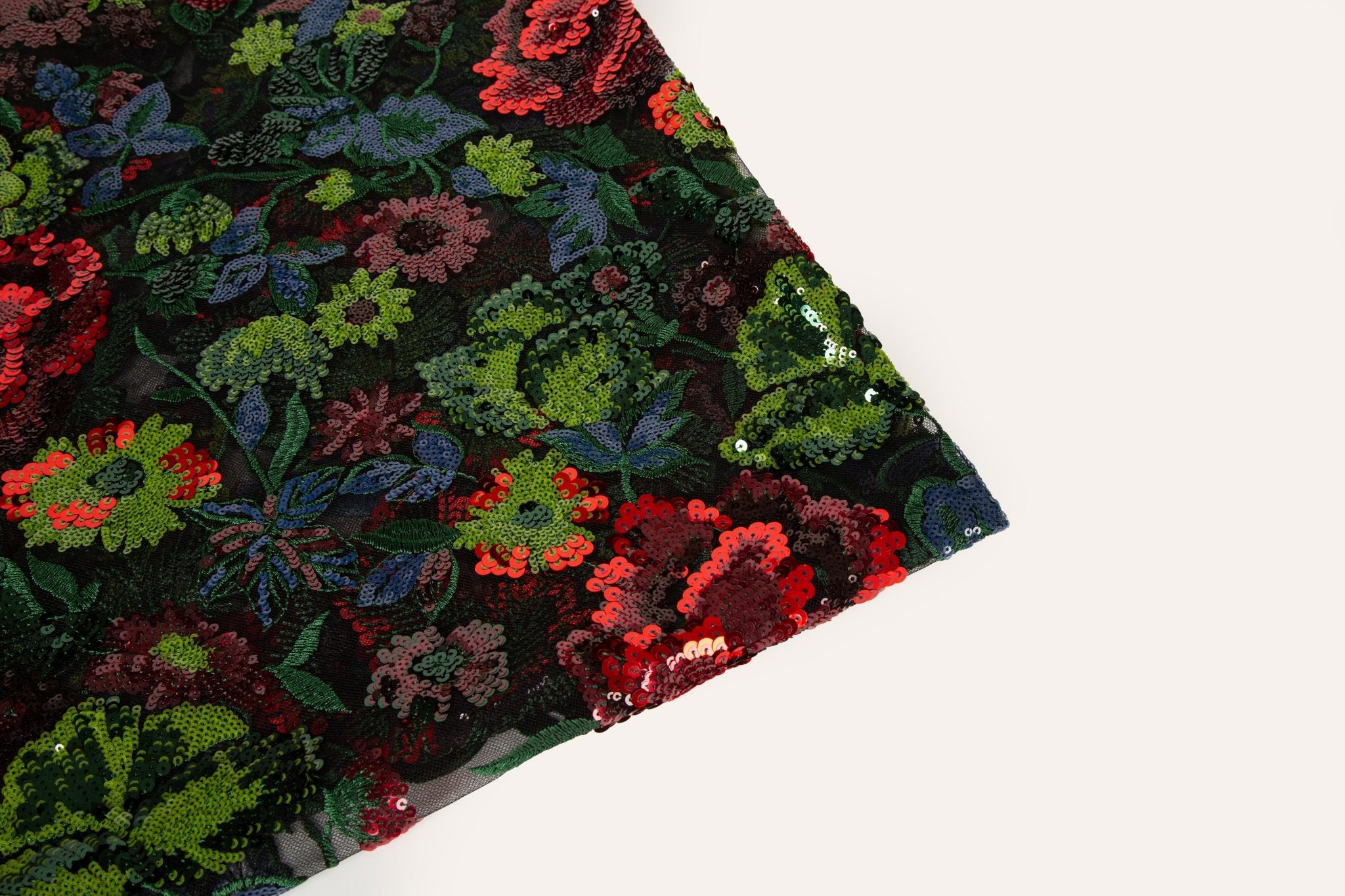A sequin floral embroidery fabric on a black base, with red and green motifs.